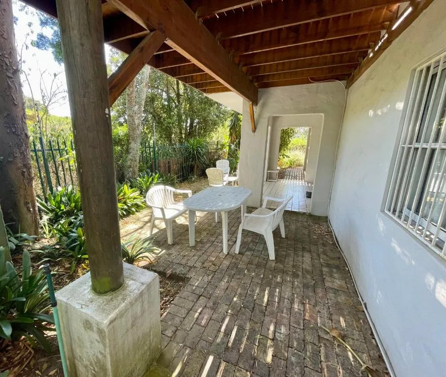Covered patio with white furniture and lush garden surroundings