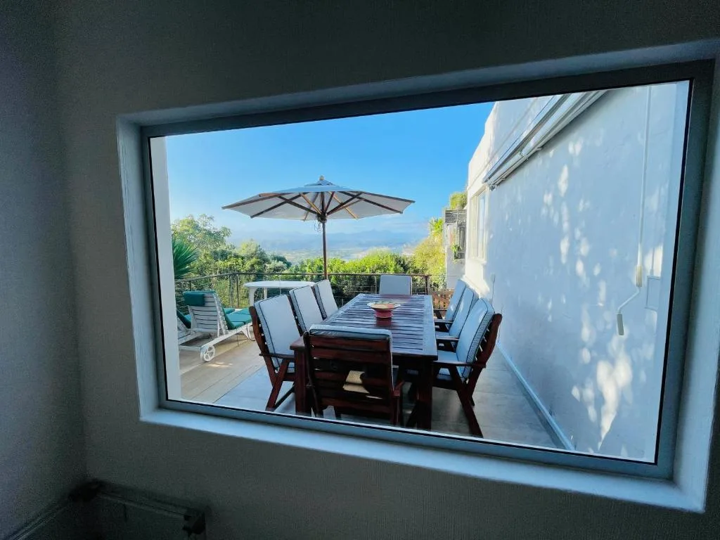 Outdoor deck with dining table, umbrella, and mountain views beyond