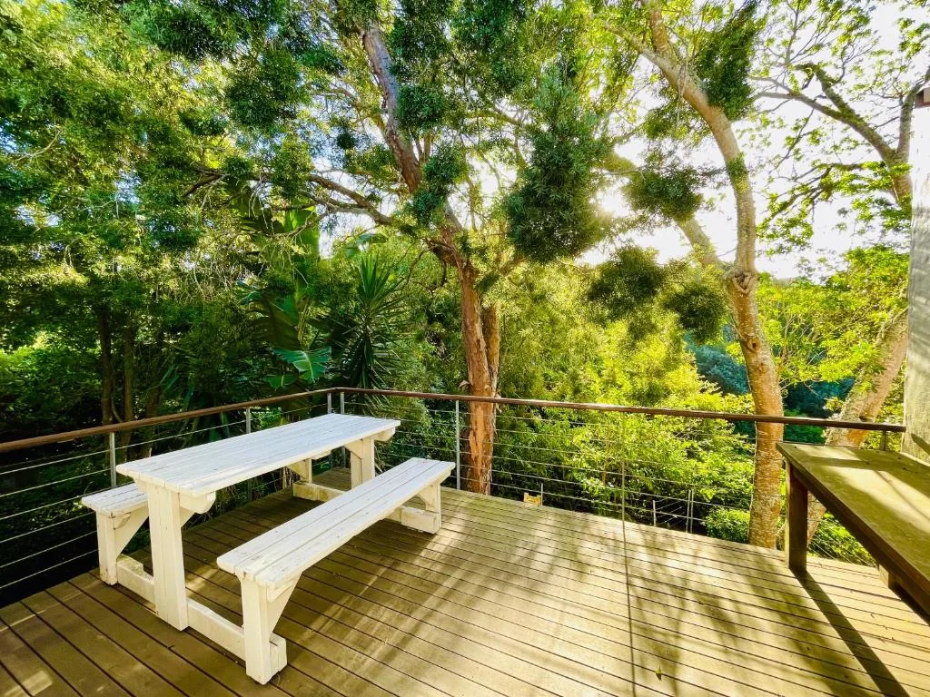 Wooden deck with picnic table overlooking lush green forest canopy