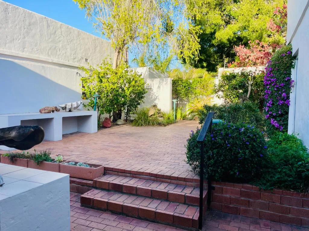 Brick patio with flowering vines, white walls, and garden seating area
