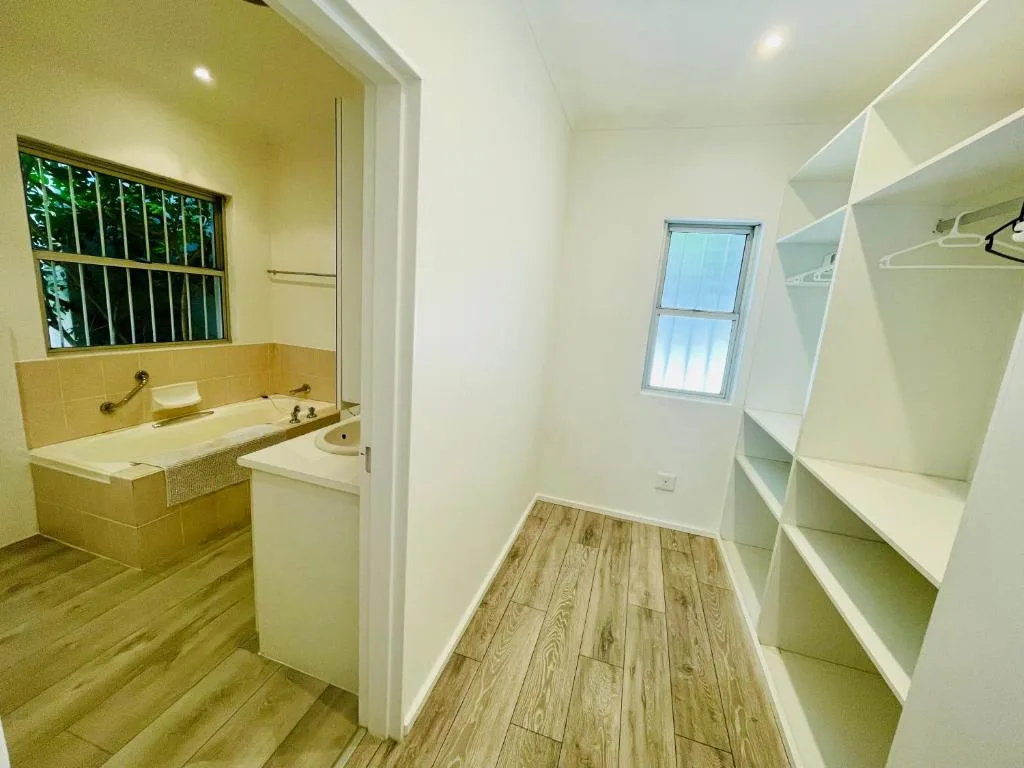 Spacious bathroom with vanity, soaking tub, and walk-in closet area