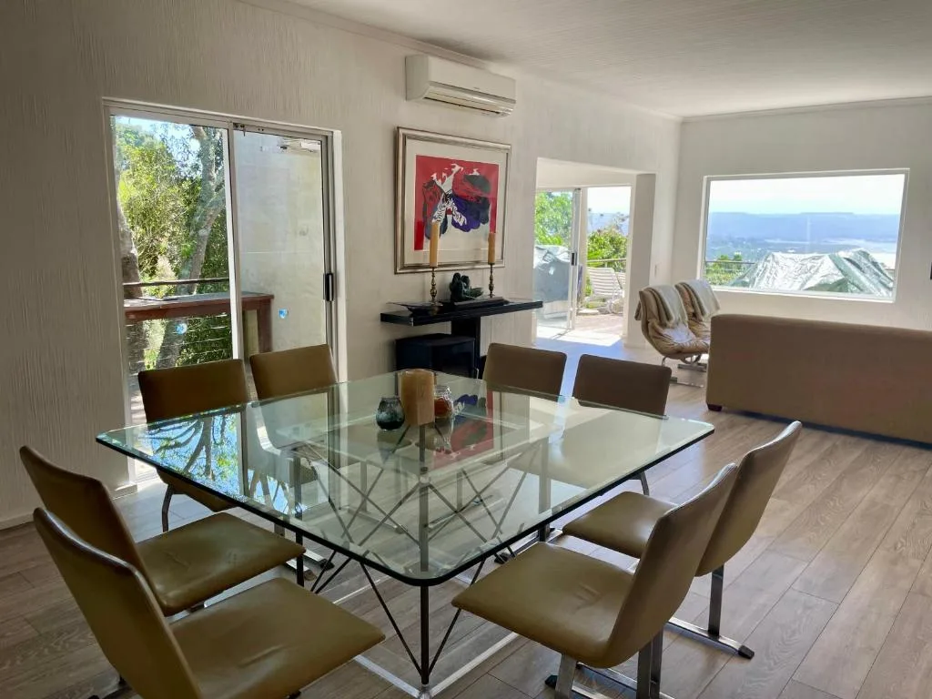 Modern glass dining table with olive chairs overlooking mountain views
