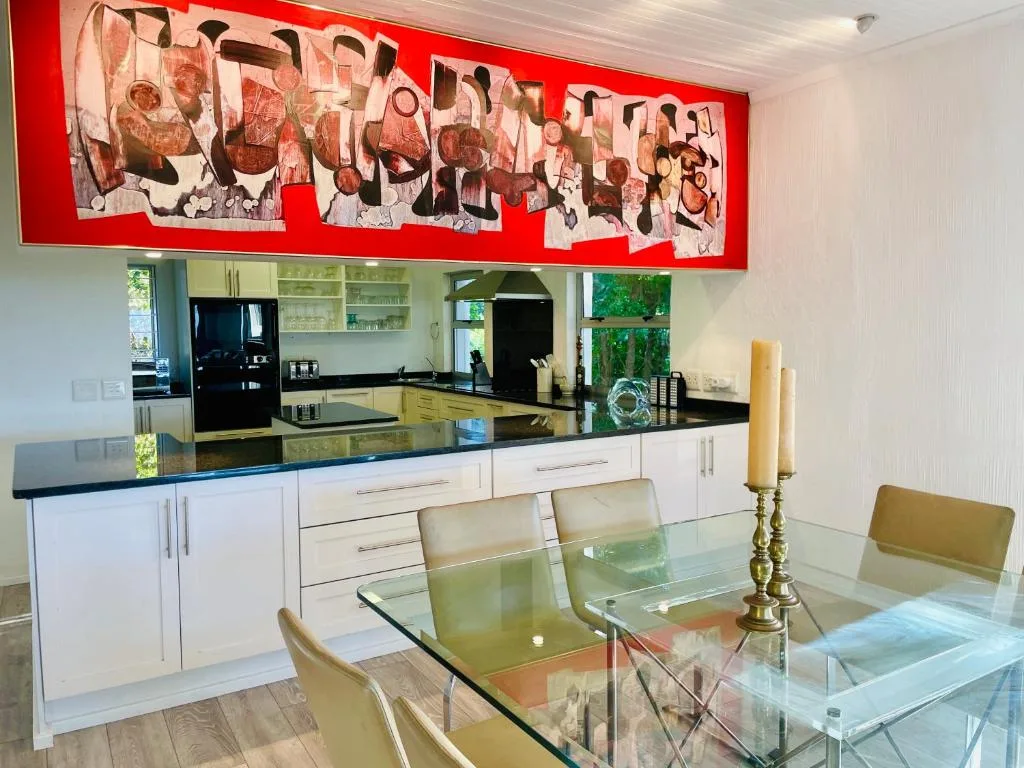 Modern kitchen with white cabinetry, black countertops, and contemporary red artwork