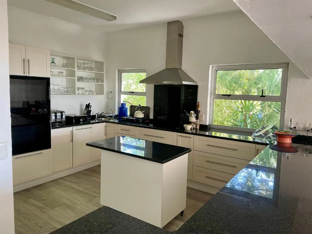 Modern cream and black kitchen with island, stove hood, and garden views