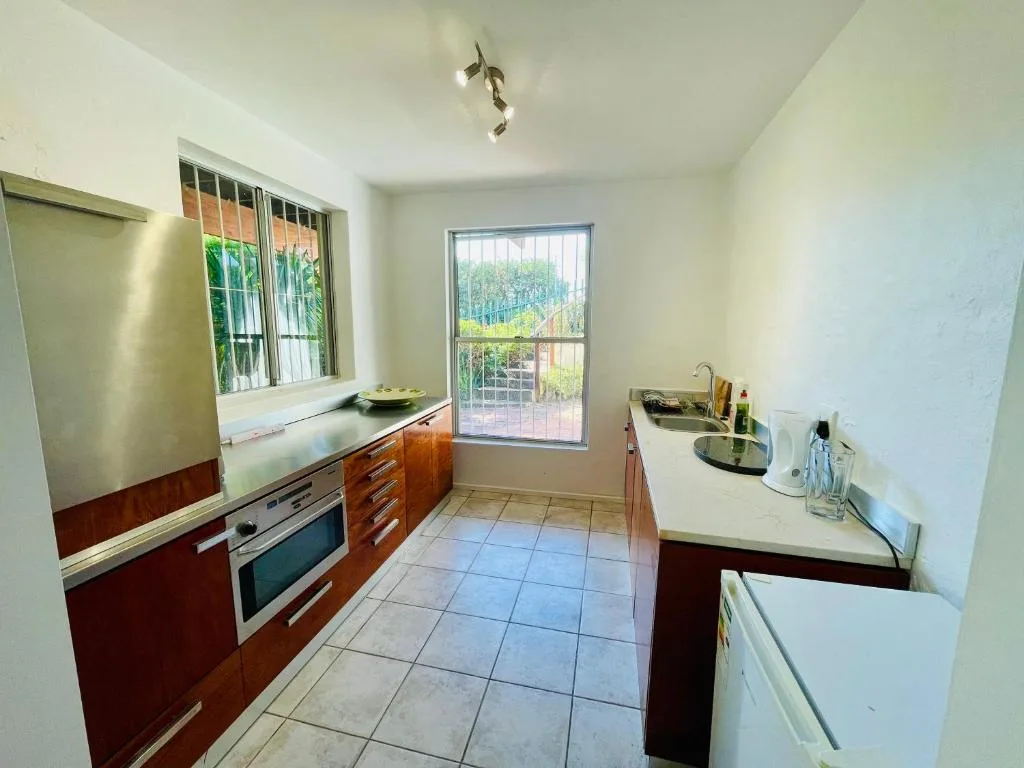 Modern kitchen with wooden cabinetry, stainless steel appliances, and garden views