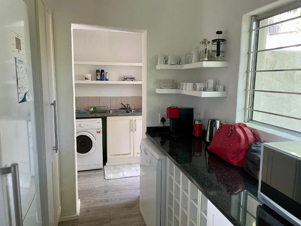 Modern kitchen with white cabinetry, dark countertops, and open shelving displaying crockery