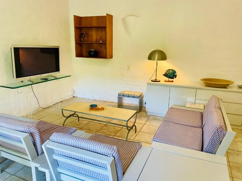Spacious lounge with striped seating, TV, and brass table lamp