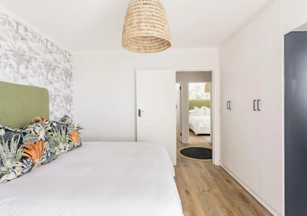 Bright modern bedroom with white bedding and tropical print pillows