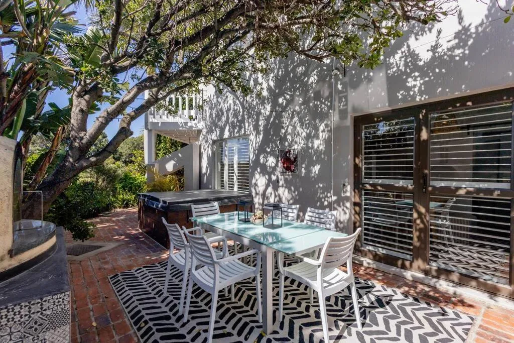 Outdoor patio with dining table, chairs, and mature tree providing shade