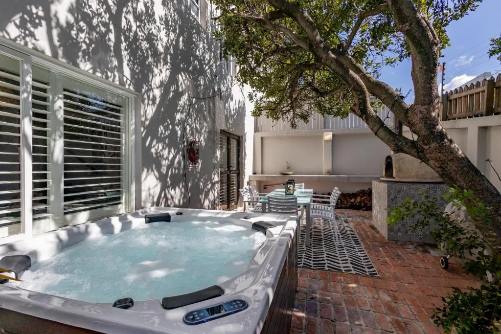 Hot tub and outdoor seating area under mature tree with brick patio