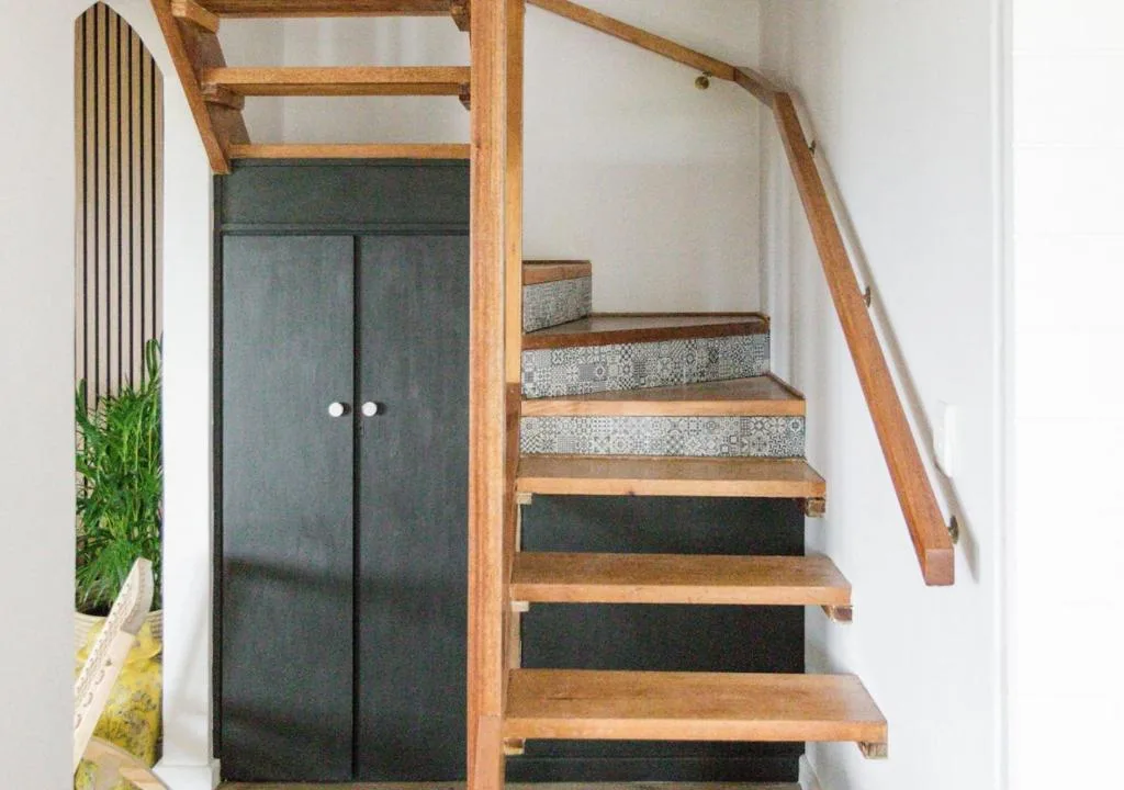 Modern wooden staircase with patterned tiles and dark wardrobe doors