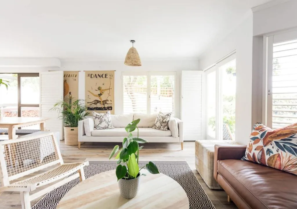 Bright open-plan lounge with cream sofa, leather chair, and plant decor