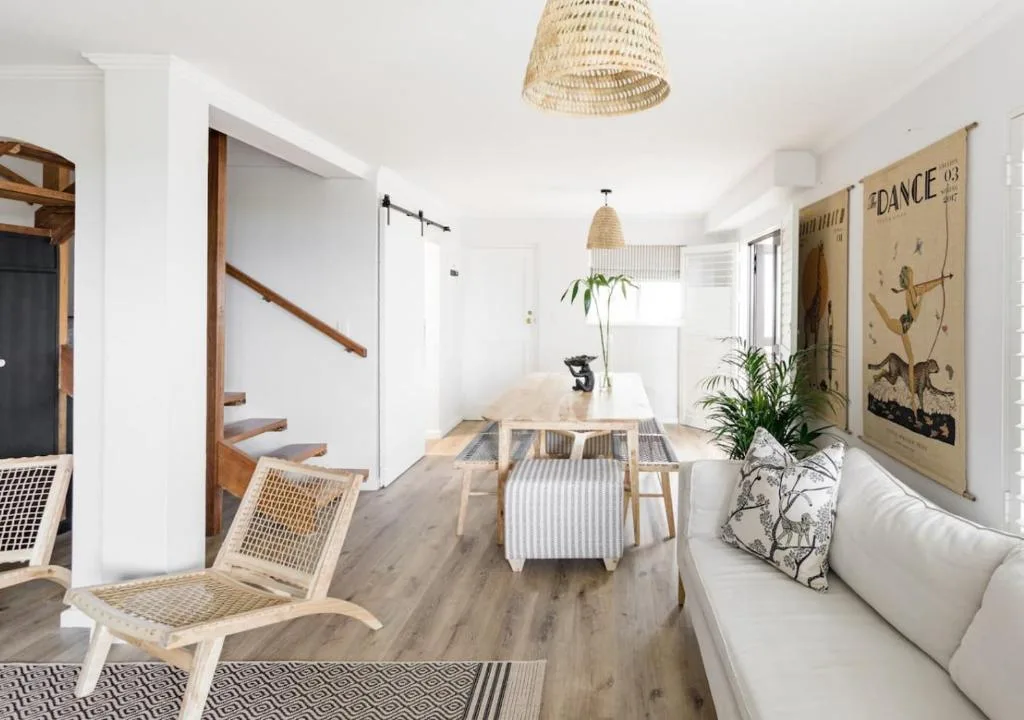 Open-plan living space with sofa, dining table, and wooden staircase