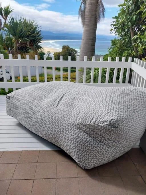 Ocean and beach vista framed by white railings and tropical palms