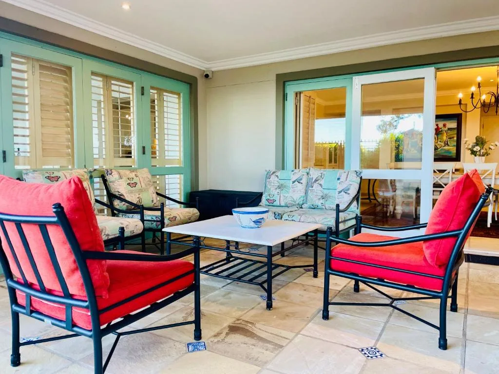 Covered patio with colorful seating and ocean views through glass doors