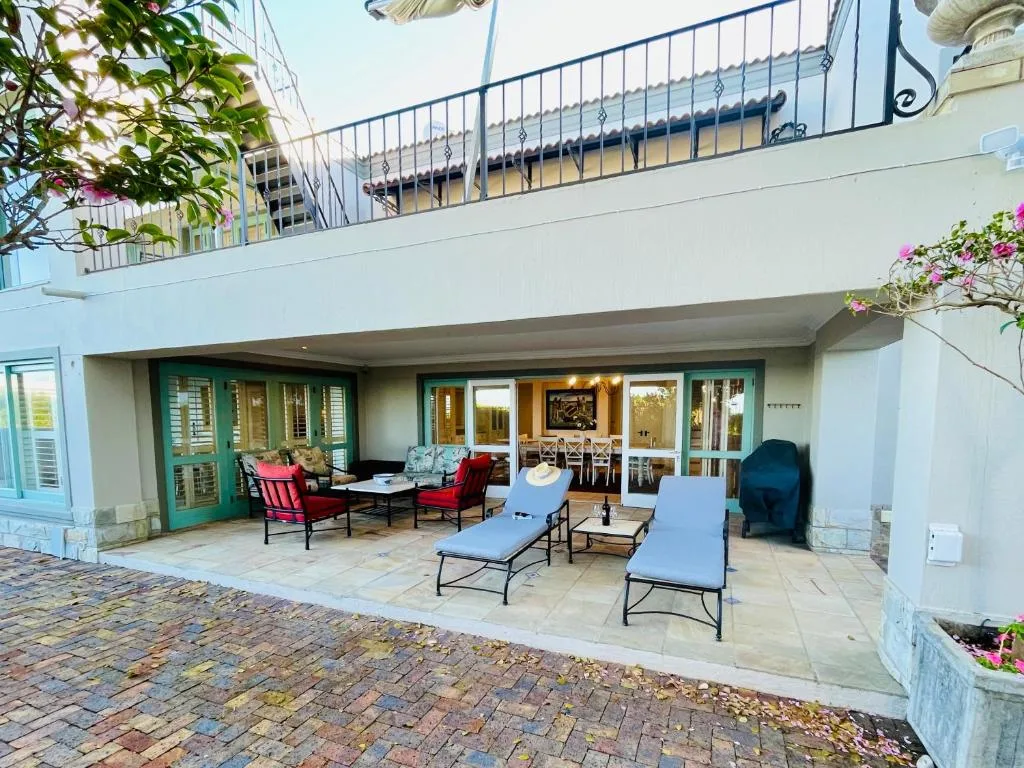 Spacious covered patio with loungers, seating area, and green doors