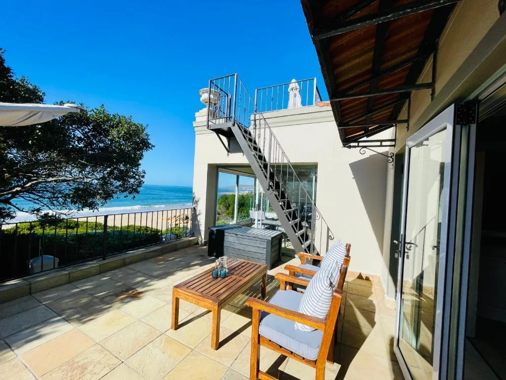 Oceanfront patio with wooden furniture and coastal views on sunny day