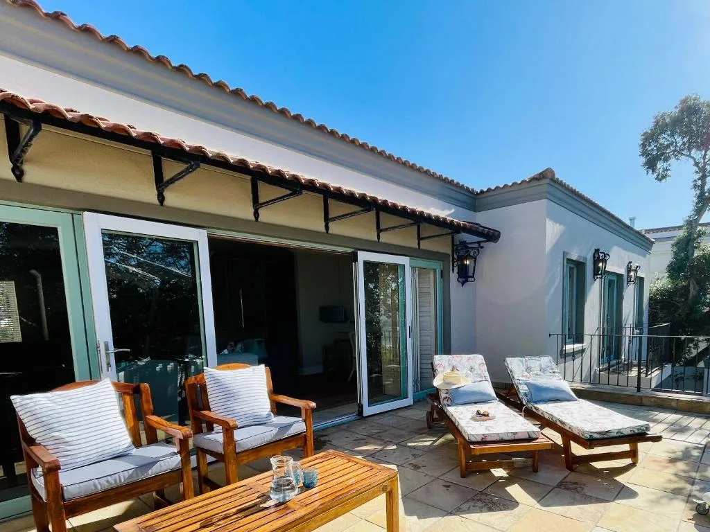 Outdoor patio with wooden furniture, loungers, and ocean views