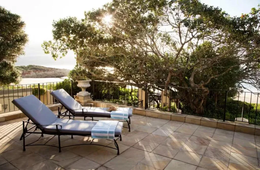 Patio with loungers overlooking lagoon and lush vegetation