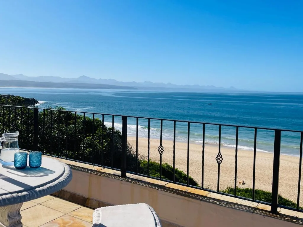 Oceanfront deck with beach views, lounge chairs, and coastal mountains