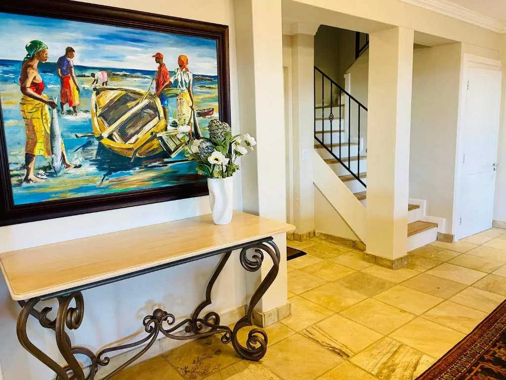 Elegant hallway with coastal artwork, decorative console table, and staircase