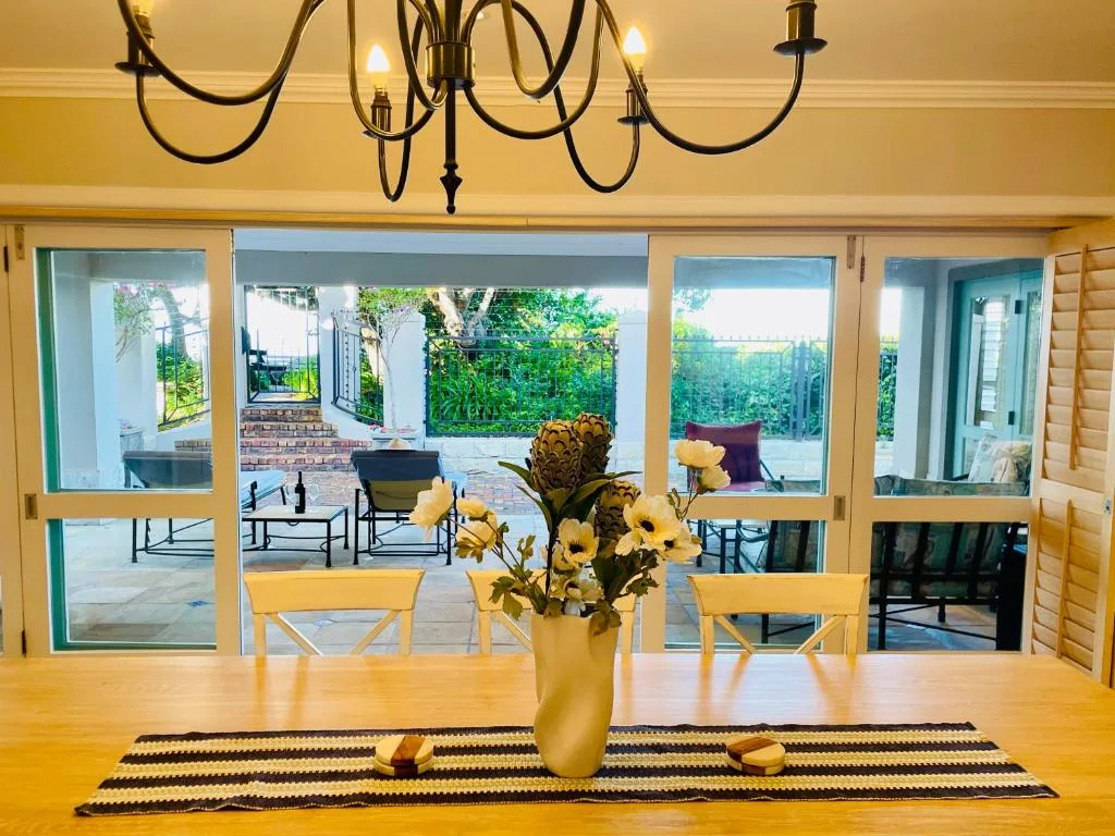 Dining table with yellow flowers and view to garden deck through glass doors