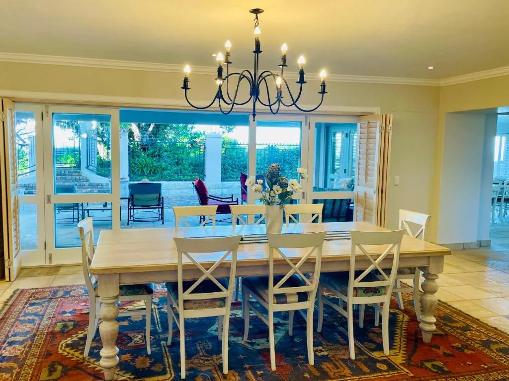 Spacious dining room with wooden table, cream chairs, chandelier, garden views