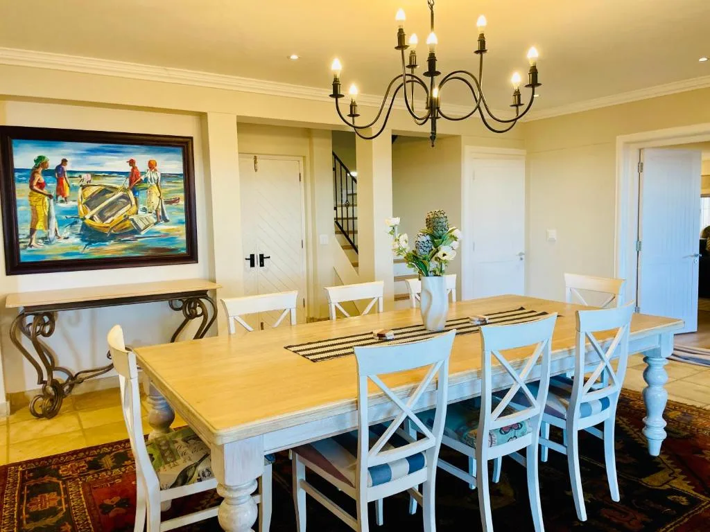 Elegant dining room with wooden table, white chairs, and decorative chandelier