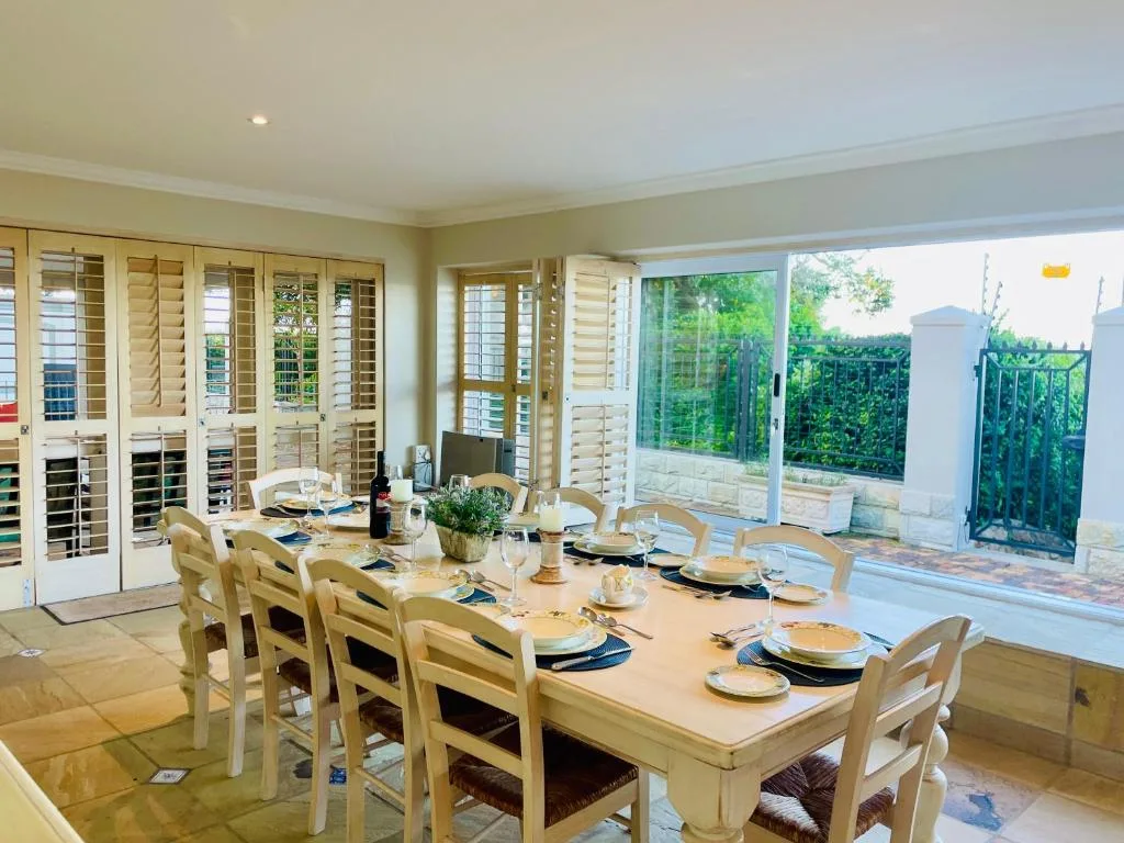 Spacious dining room with long wooden table and eight chairs, overlooking garden