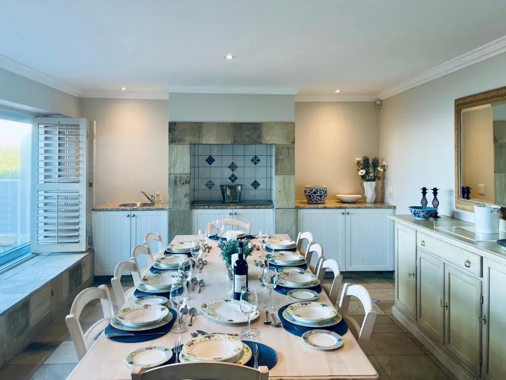 Elegant dining room with long table, blue place settings, and kitchen views