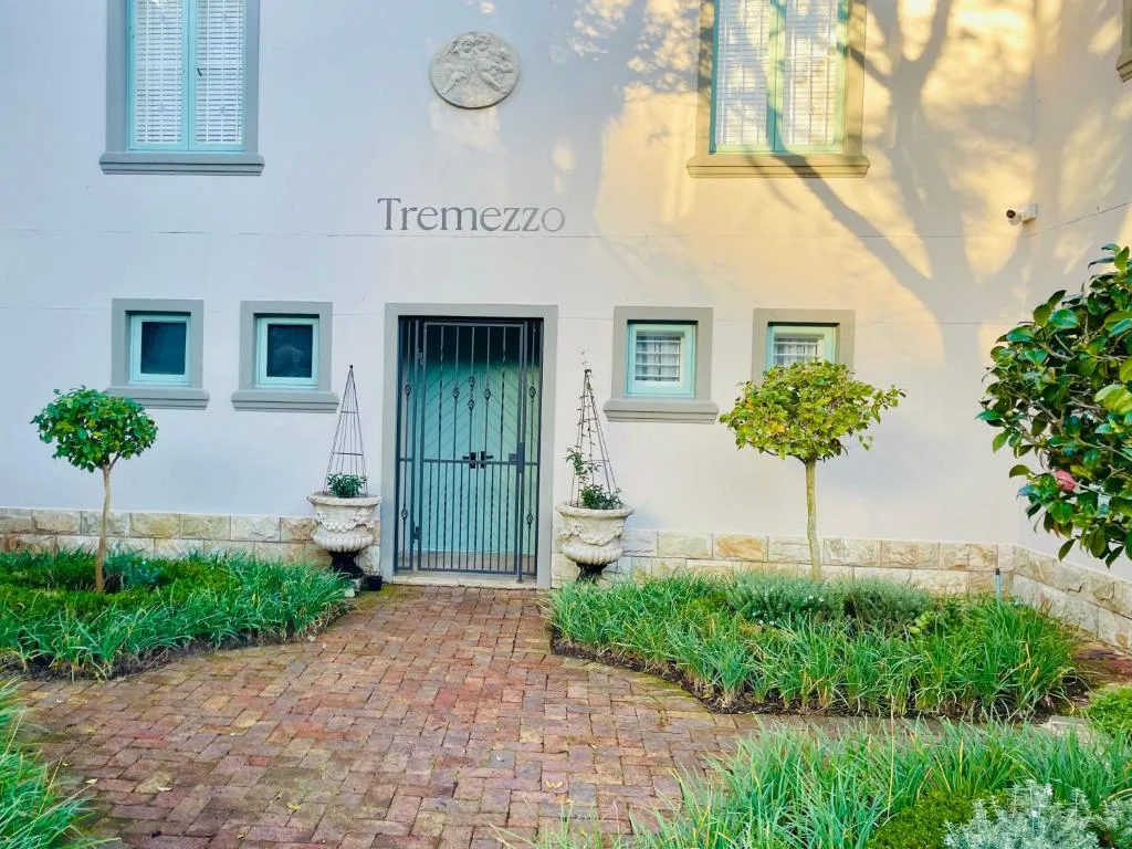 White villa facade with turquoise shutters, green entrance door, and landscaped gardens