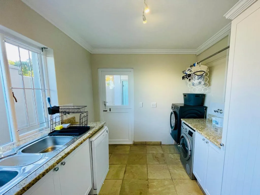Bright kitchen with sink, washing machines, granite counters, and garden window