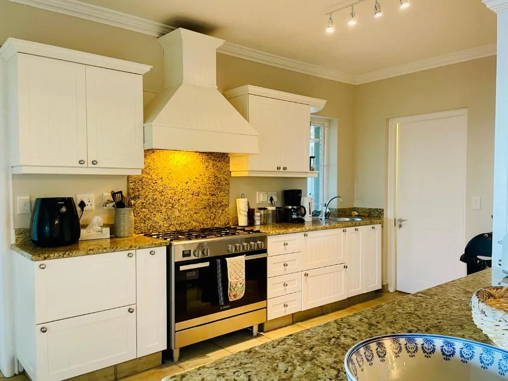 Modern kitchen with cream cabinetry, granite countertops, and stainless steel range