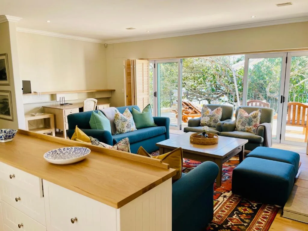 Open-plan lounge with blue sofas, wooden counter, and garden views