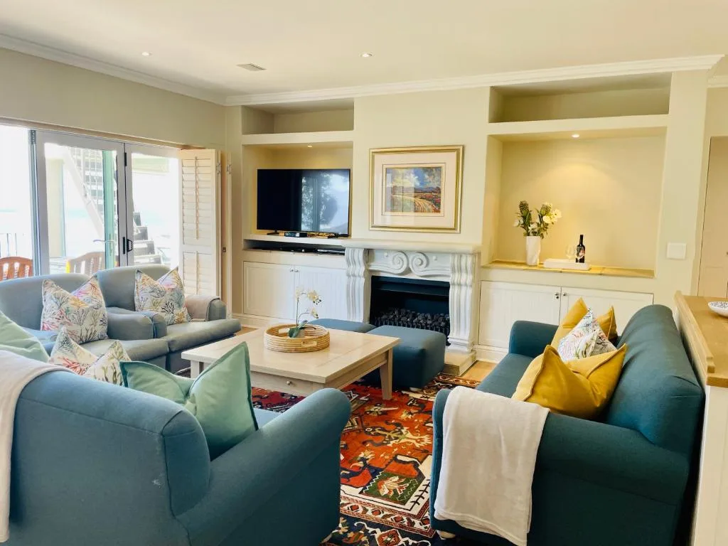 Spacious lounge with teal armchairs, fireplace, TV, and deck access