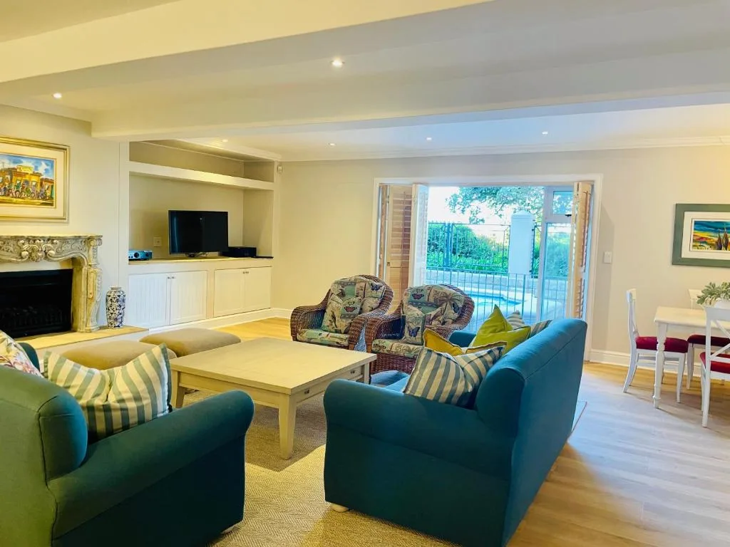 Spacious living room with teal sofas, fireplace, TV, and garden views
