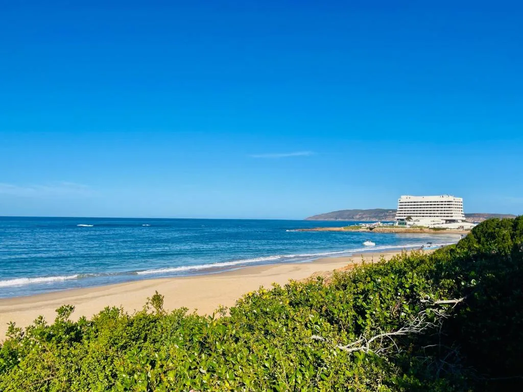 Pristine sandy beach with turquoise ocean and coastal mountains in distance