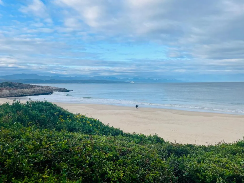 Scenic beach and ocean view with distant mountains and coastal cliffs
