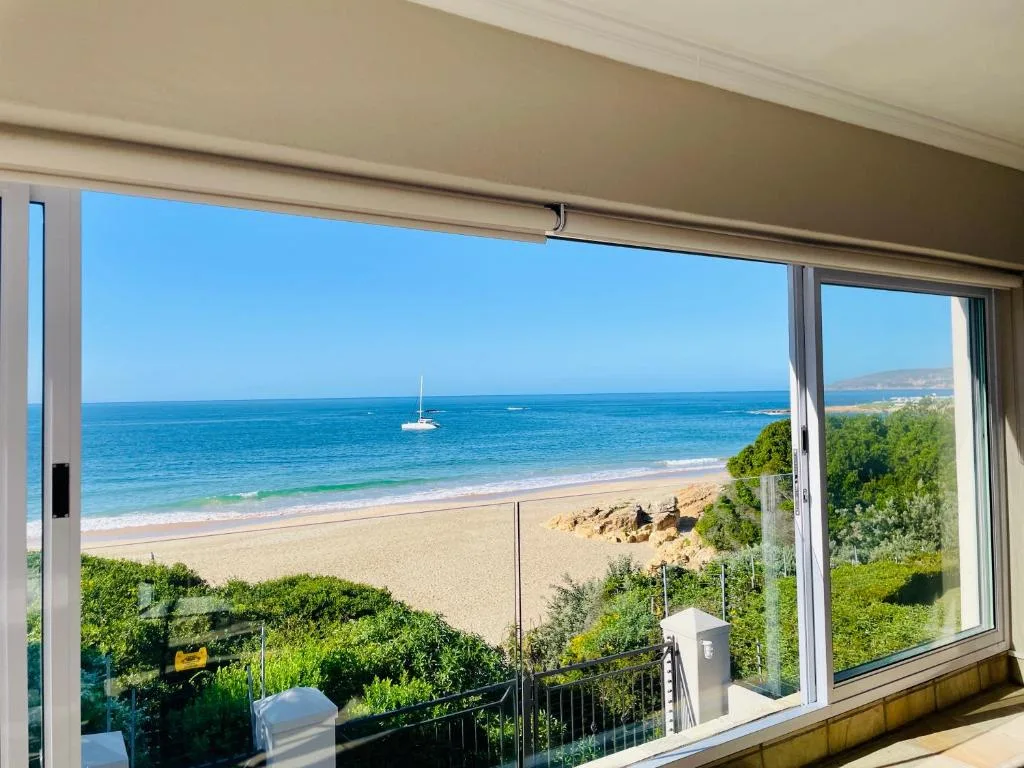 Stunning ocean view with pristine beach, sailboat, and coastal landscape