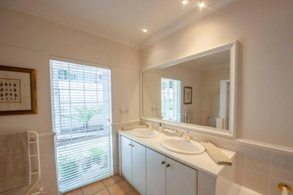 Bright bathroom with dual vanity sinks and large mirror overlooking garden