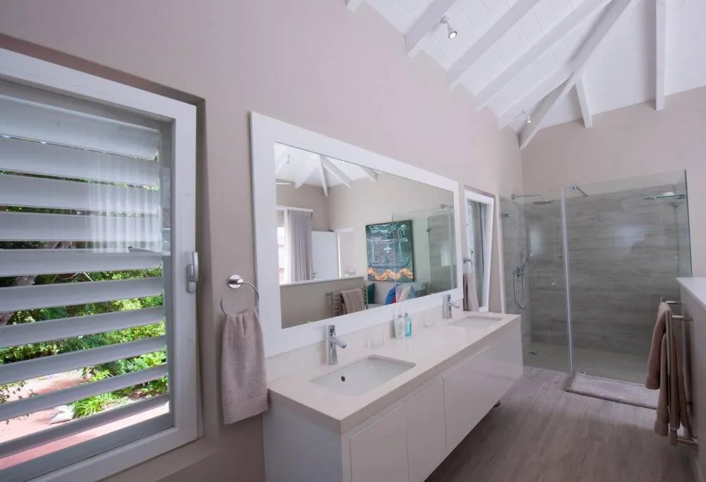 Modern bathroom with double vanity, large mirror, and walk-in shower enclosure