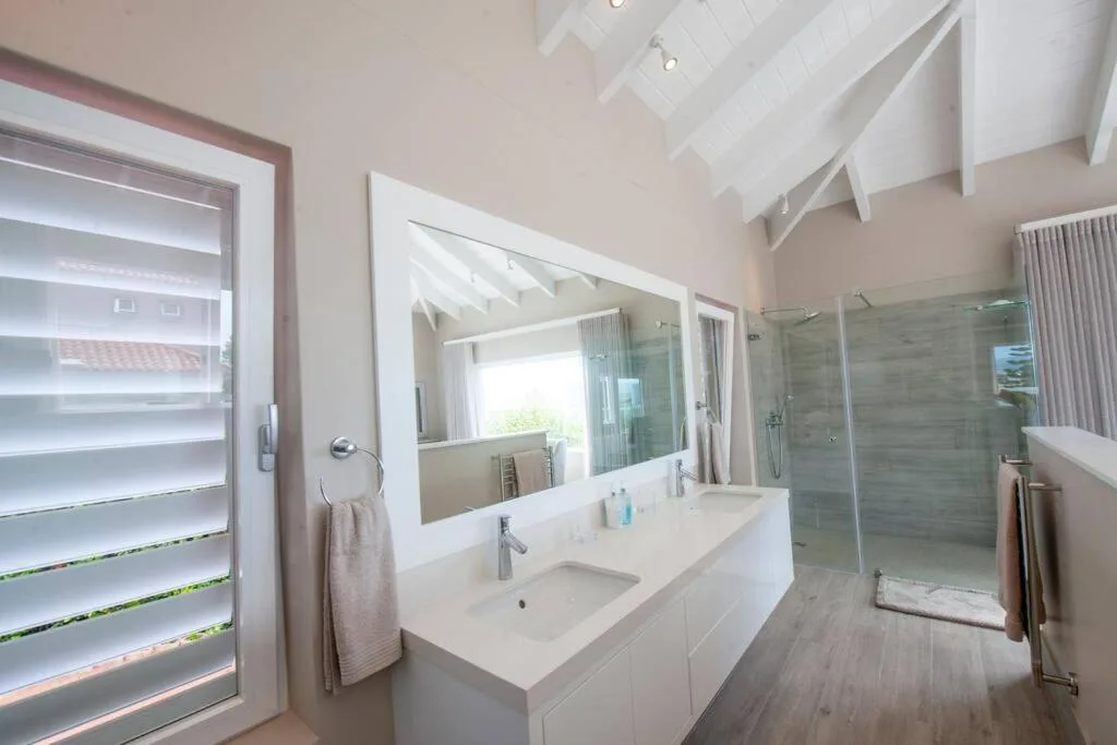 Modern bathroom with double vanity, large mirror, and walk-in shower enclosure
