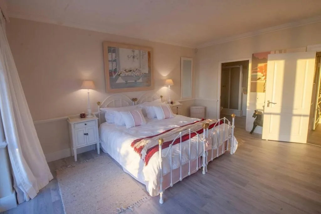 Spacious bedroom with white metal bed frame and ensuite bathroom doorway visible