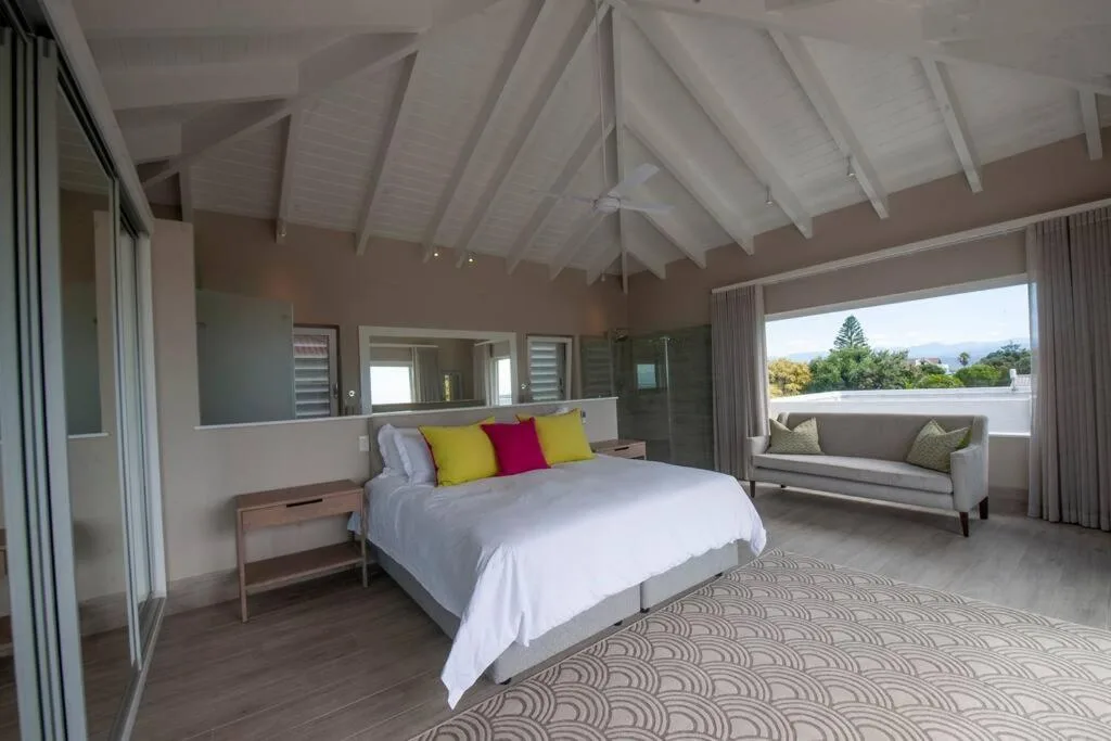 Spacious bedroom with vaulted ceiling, queen bed, and mountain views through windows