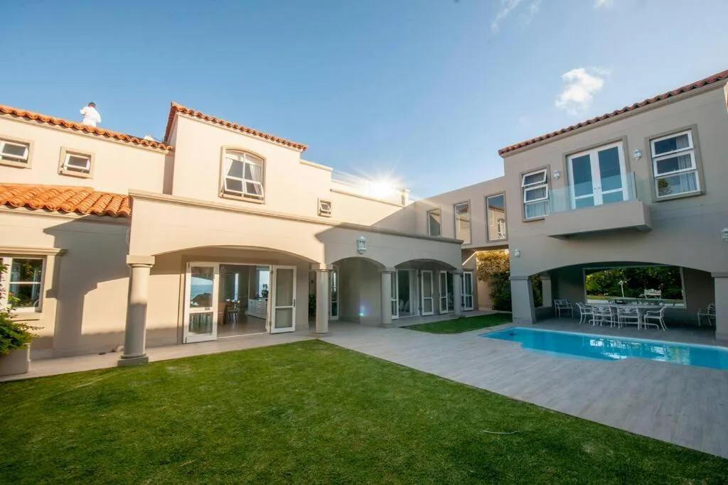 Modern villa courtyard with pool, manicured lawn, and covered terraces