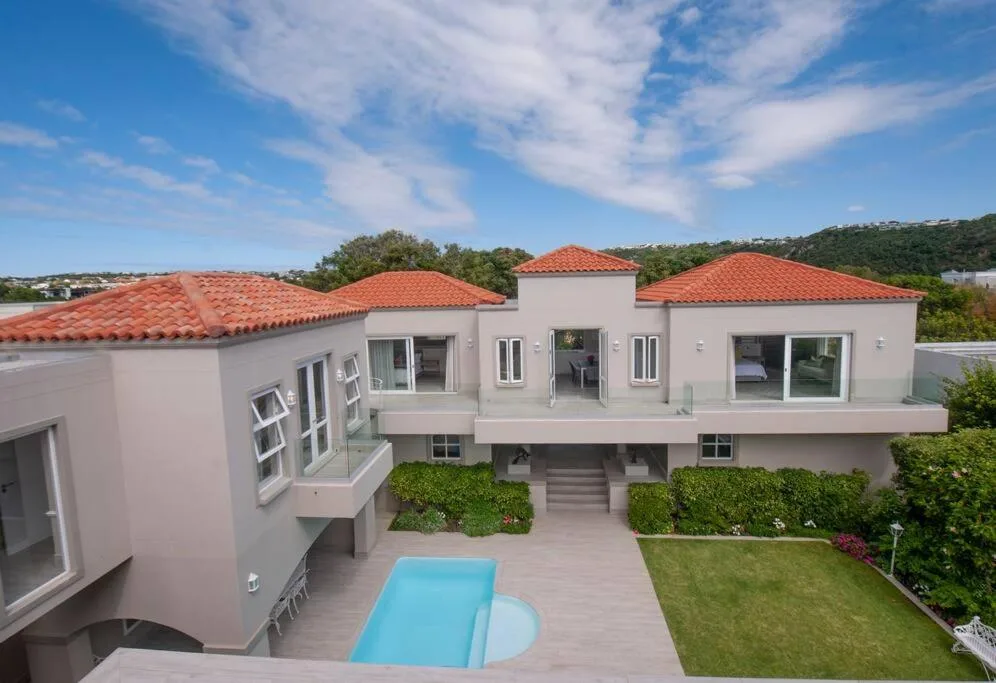 Modern villa with terracotta roof, white walls, pool, and manicured gardens