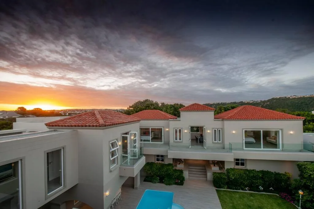 Modern white villa with red tile roof at sunset, scenic coastal views