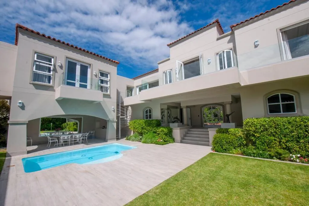 Modern white villa with pool, manicured gardens, and covered terrace area