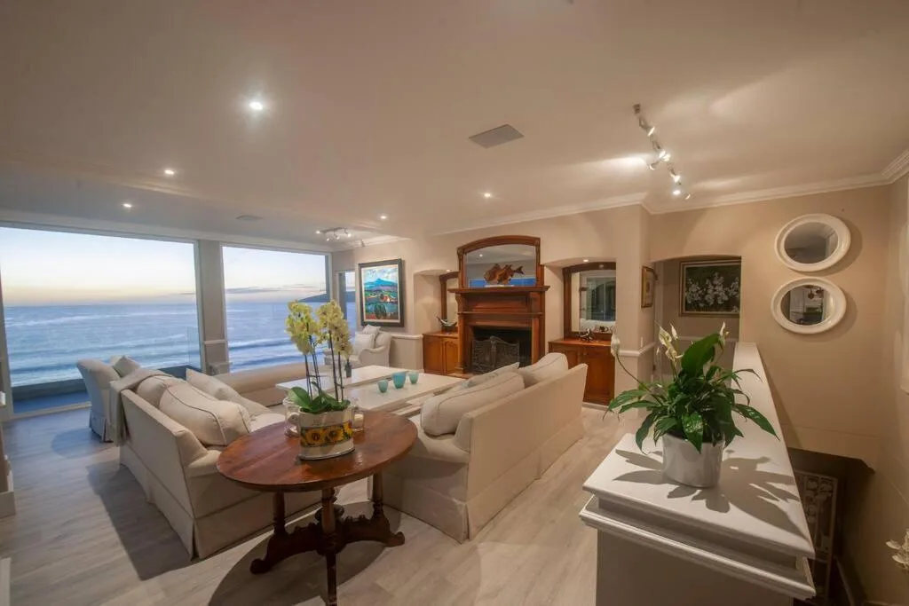 Spacious lounge with cream sofas, fireplace, and ocean views