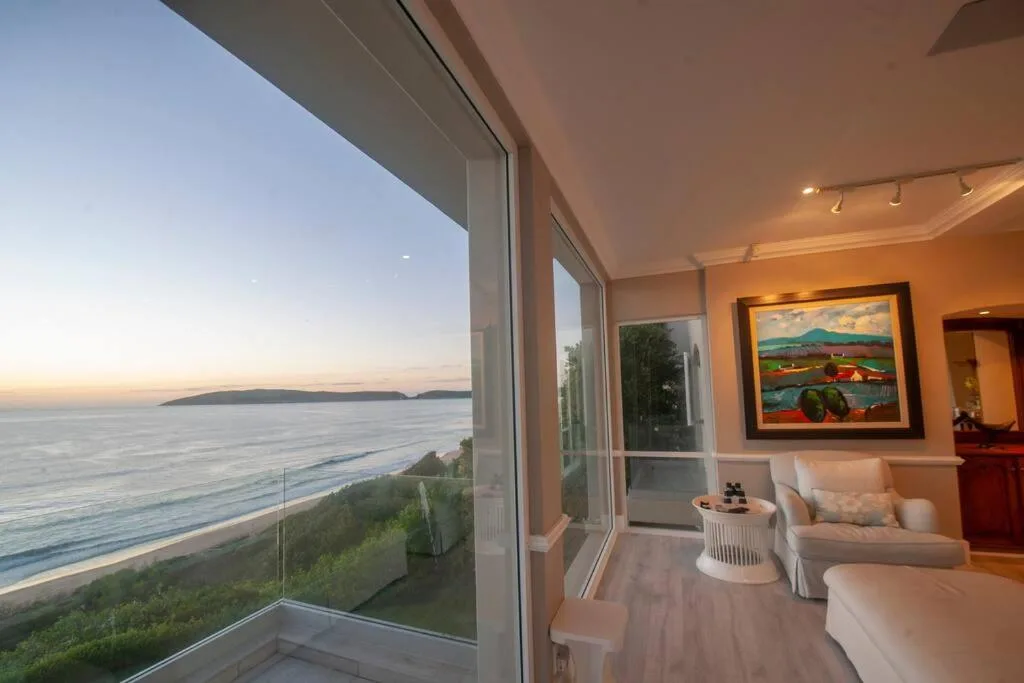 Modern lounge with ocean views through floor-to-ceiling windows and artwork